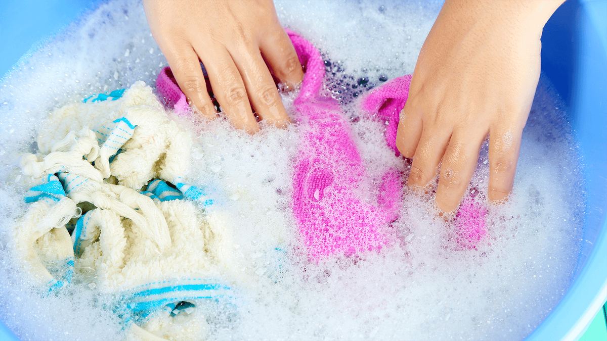 Delicate garments being gently washed by hand in soapy water