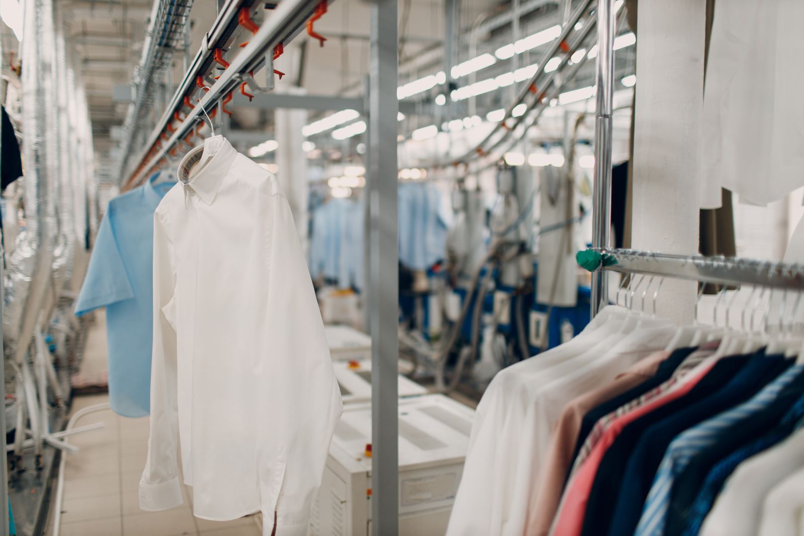 Pressed white and colored shirts on the conveyor rail inside a professional cleaning plant